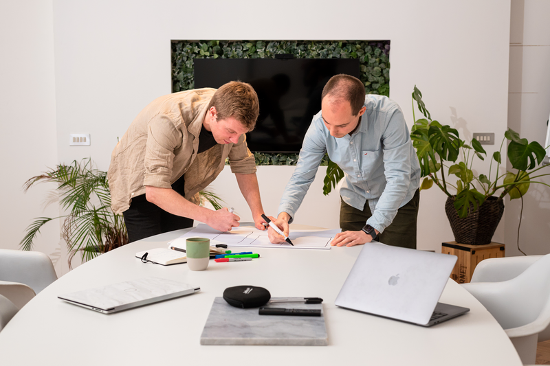 Twee teamleden schetsen samen een websiteflow op papier.